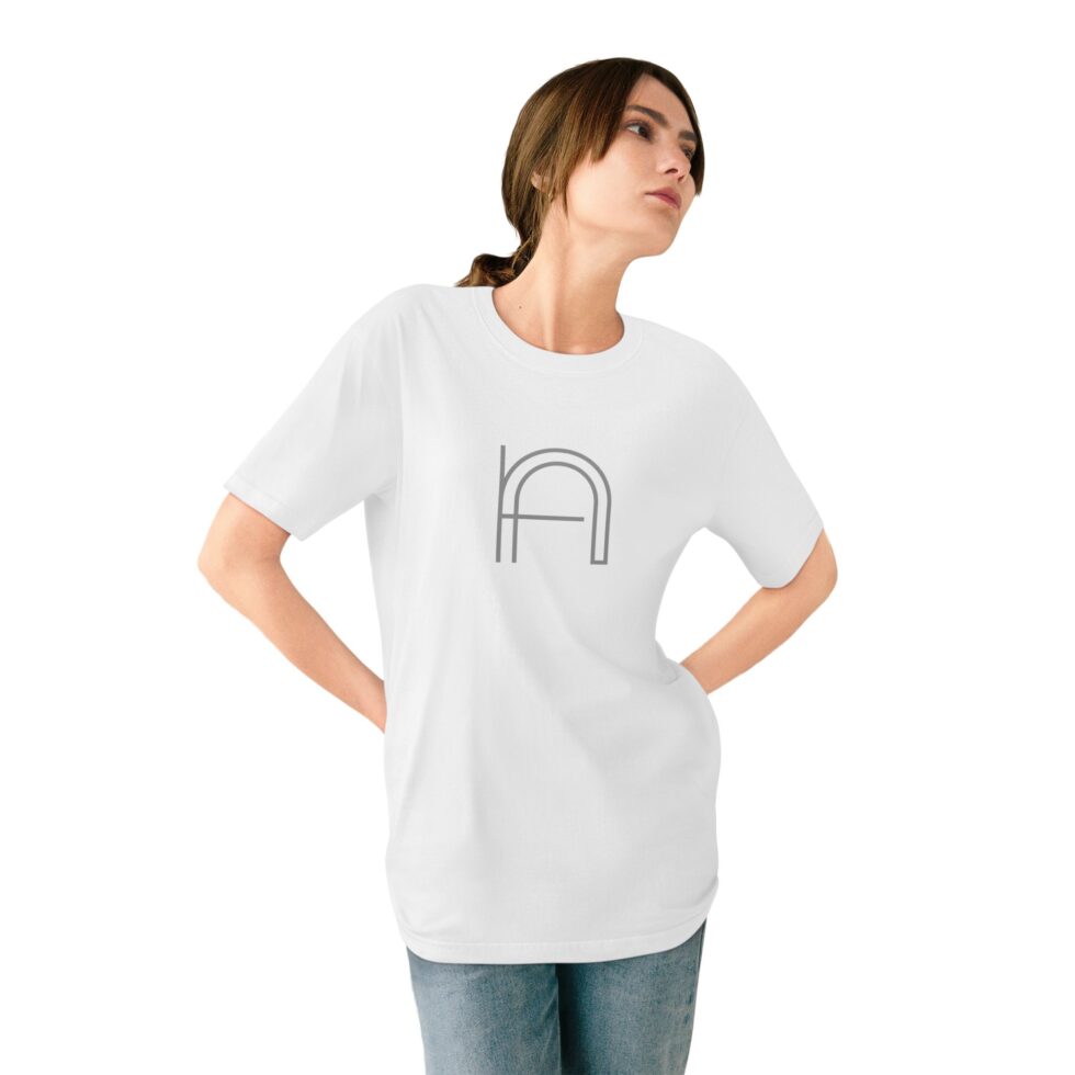 A photo of a young female model wearing a white color unisex tee shirt with a grey minimalist grey graphic NA tee shirt design.