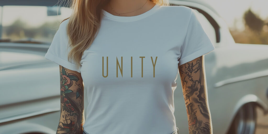 Cropped photo of a young woman with tattoos wearing a white unity NA tee shirt with a minimal graphic design.